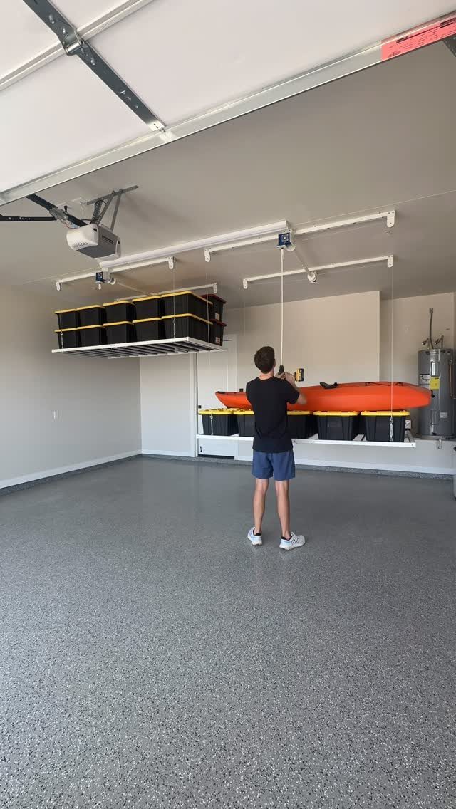 Man operating a ceiling hoist system for storage in a clean modern garage