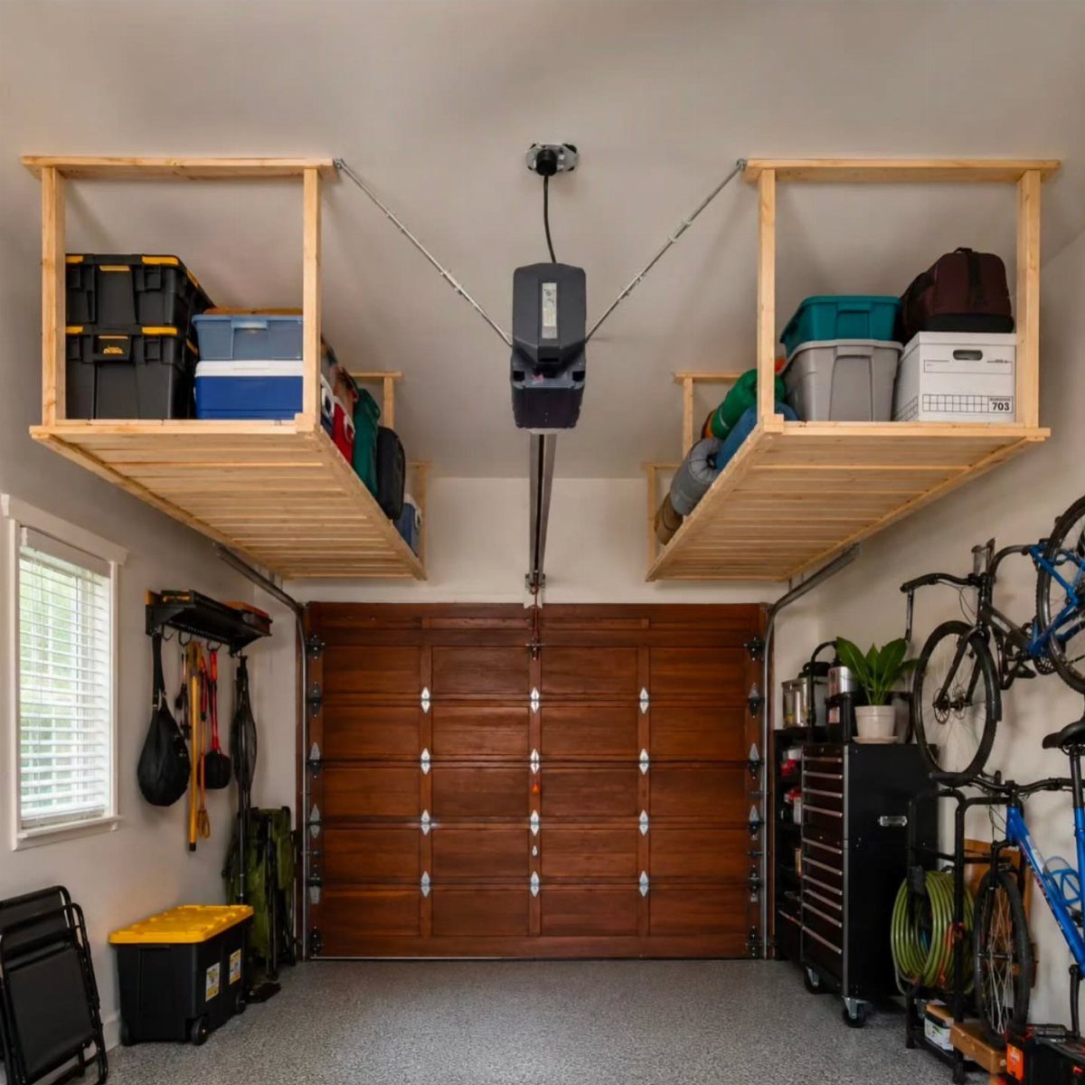 Wooden overhead storage shelves holding plastic bins in a clean, organized home garage.