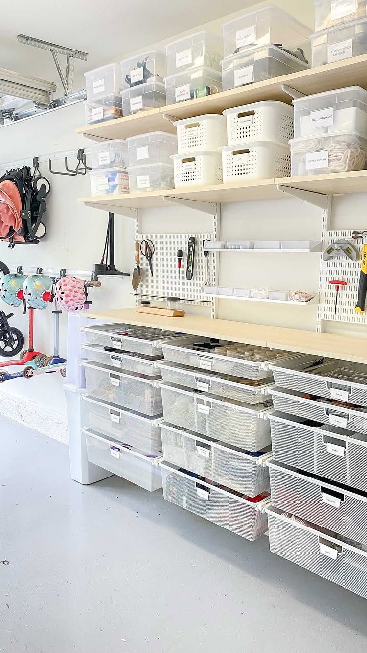 Garage workshop with a workbench, clear storage bins, and a white tool pegboard.