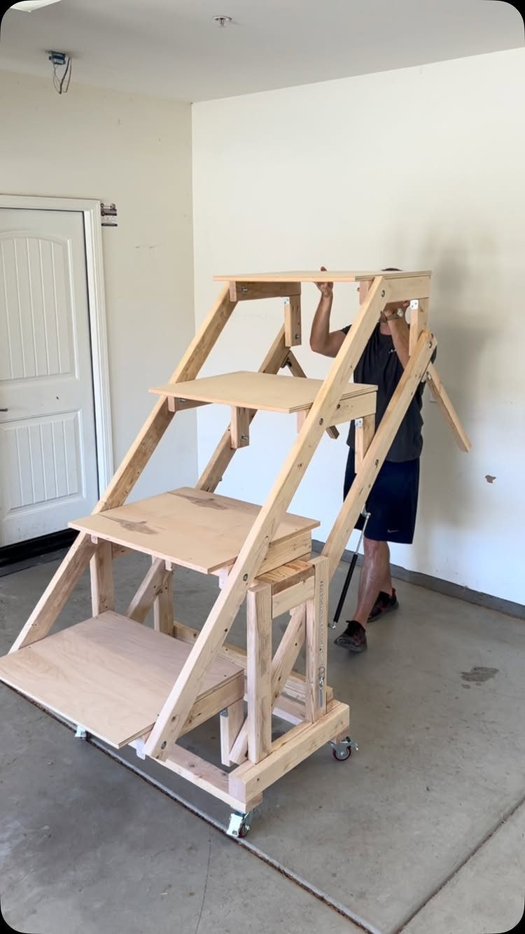 Wooden rolling multi-tier platform in a white garage with a man standing behind it.