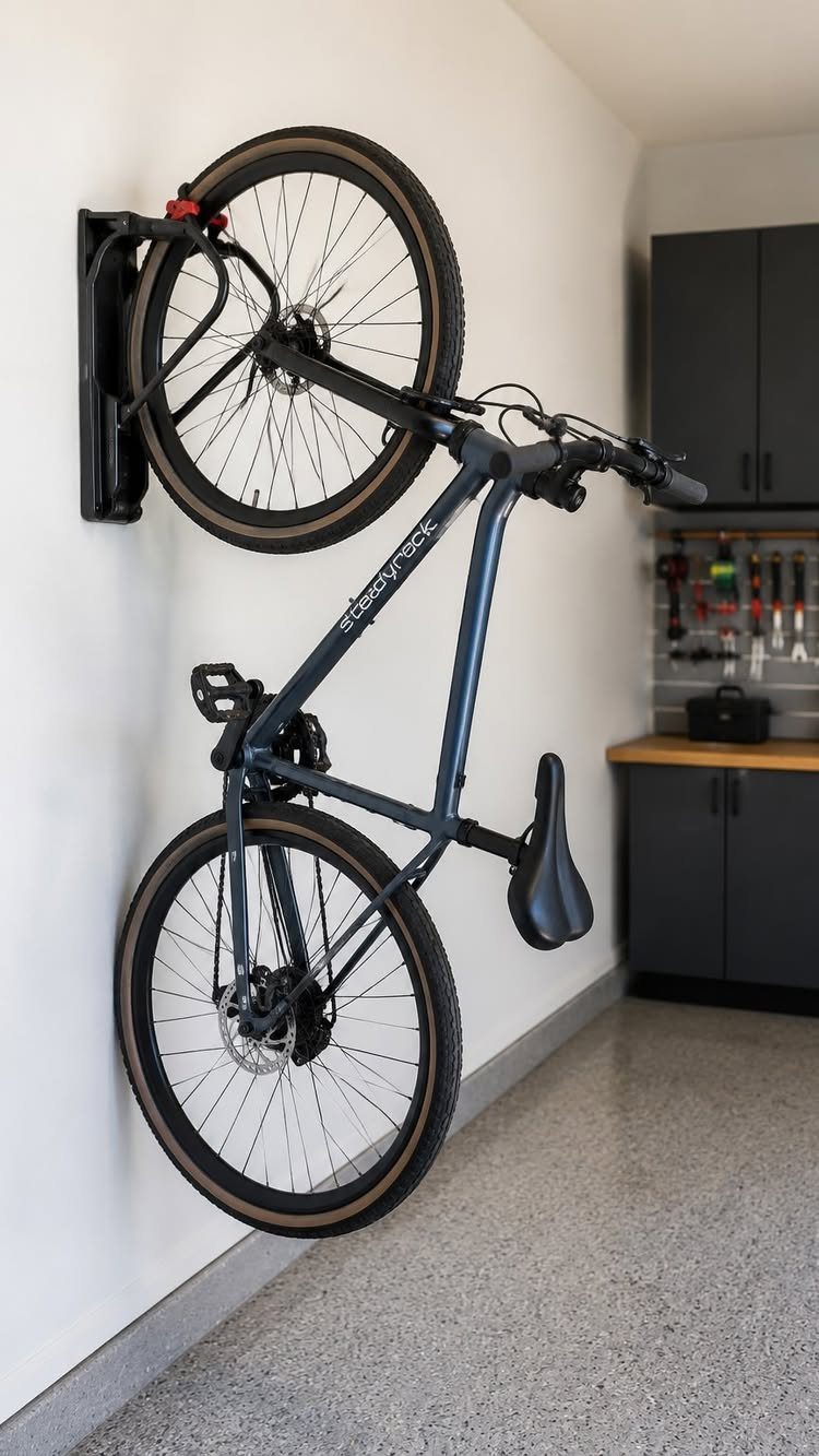 Blue bicycle held vertically by a black wall-mounted rack in a clean garage.