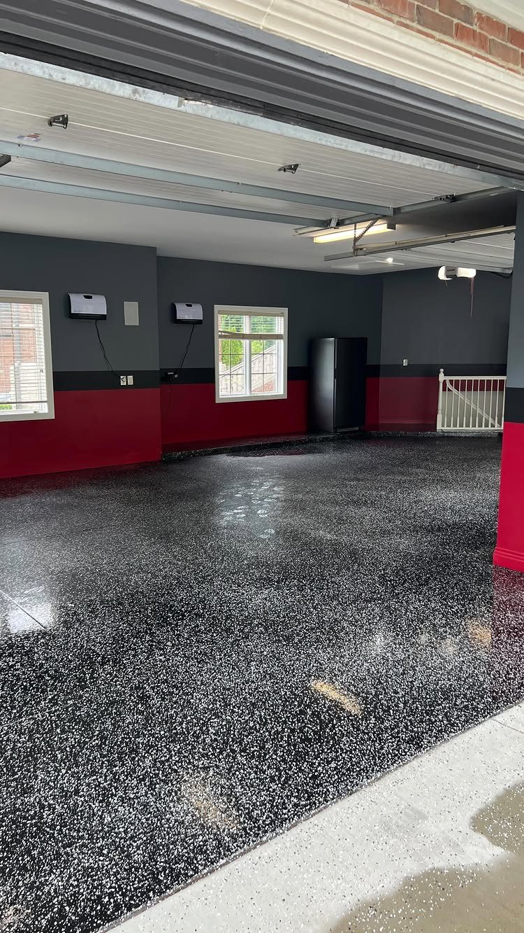 Glossy black epoxy garage floor with decorative flakes and red and grey walls.