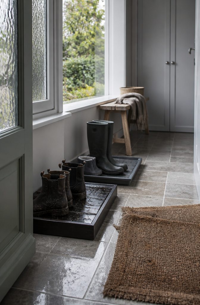 Damp boots on a black-stained pine tray and a polypropylene tray