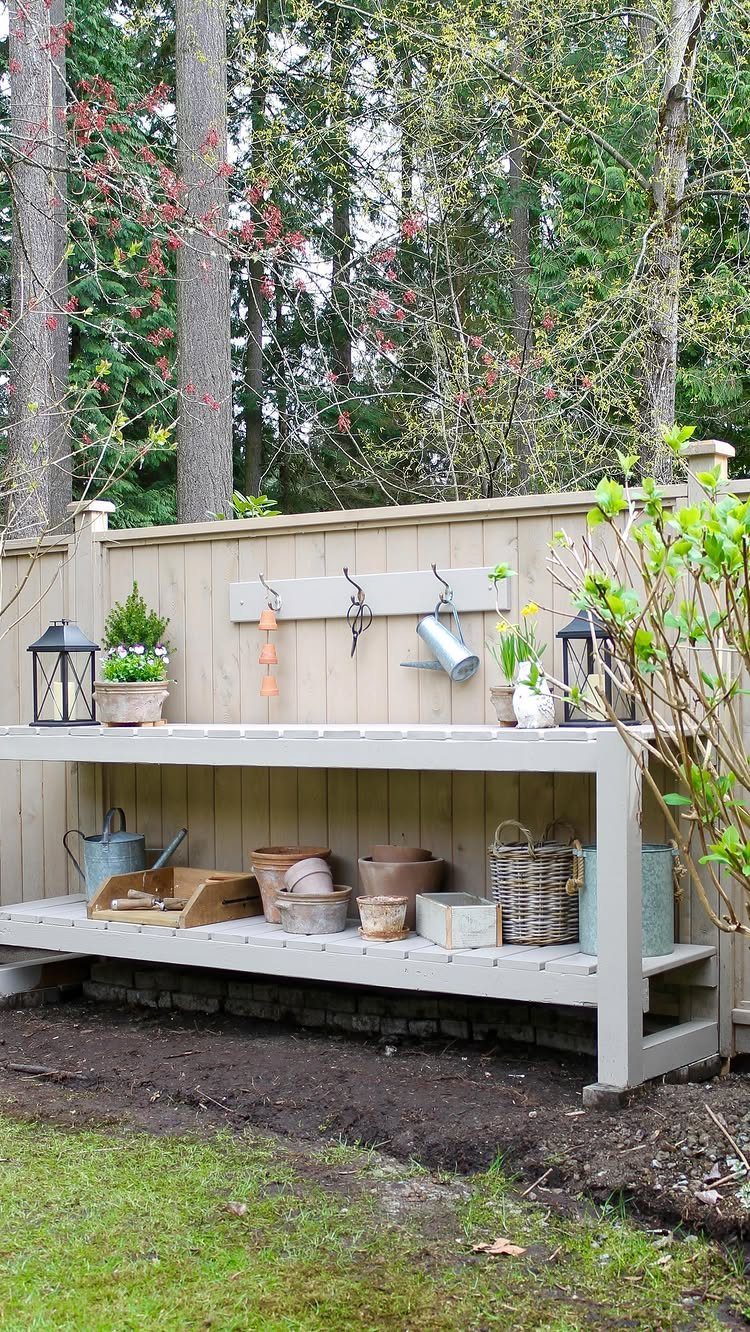 Wooden potting bench with shelves and wall hooks holding garden tools and pots.