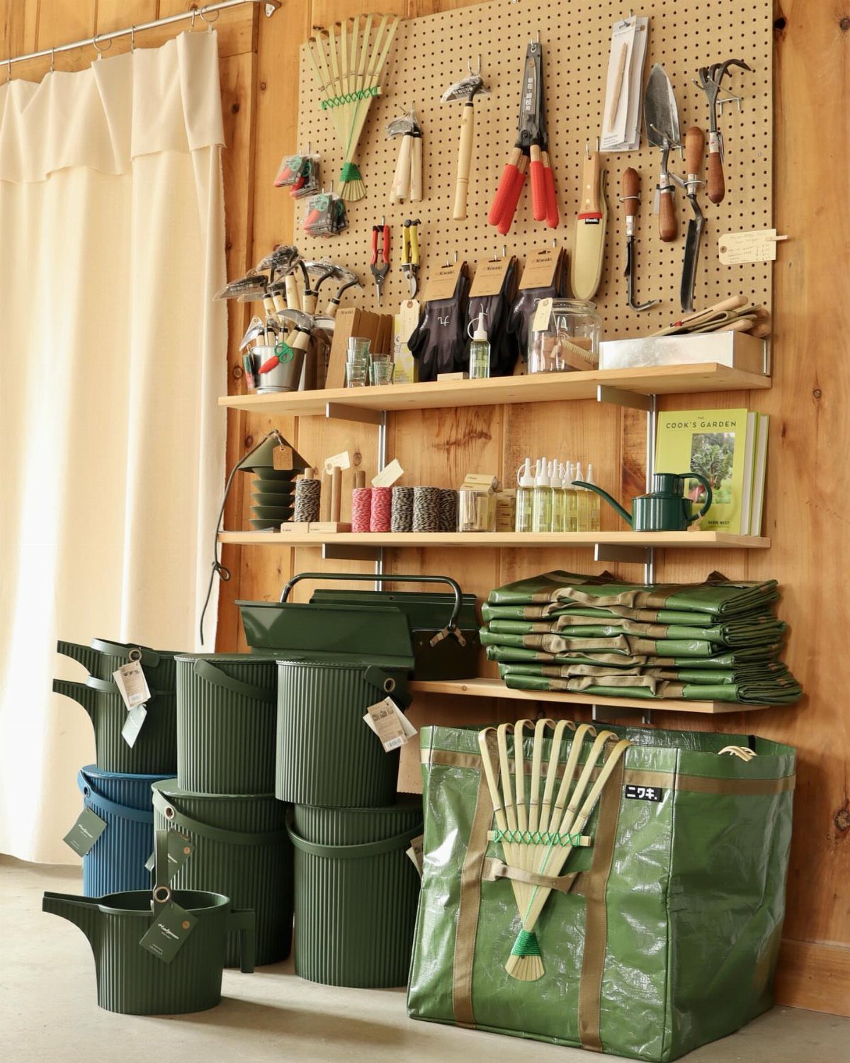 Garden tools organized on a pegboard and wooden shelves with watering cans below.