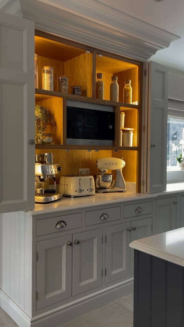Grey kitchen cabinet with open doors revealing a microwave, toaster, and stand mixer.