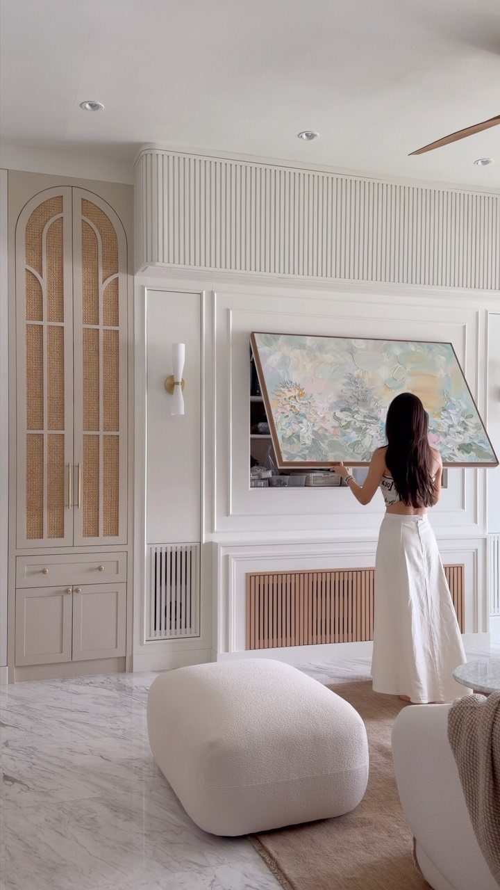 Woman sliding a painting to reveal a hidden wall compartment in a modern room