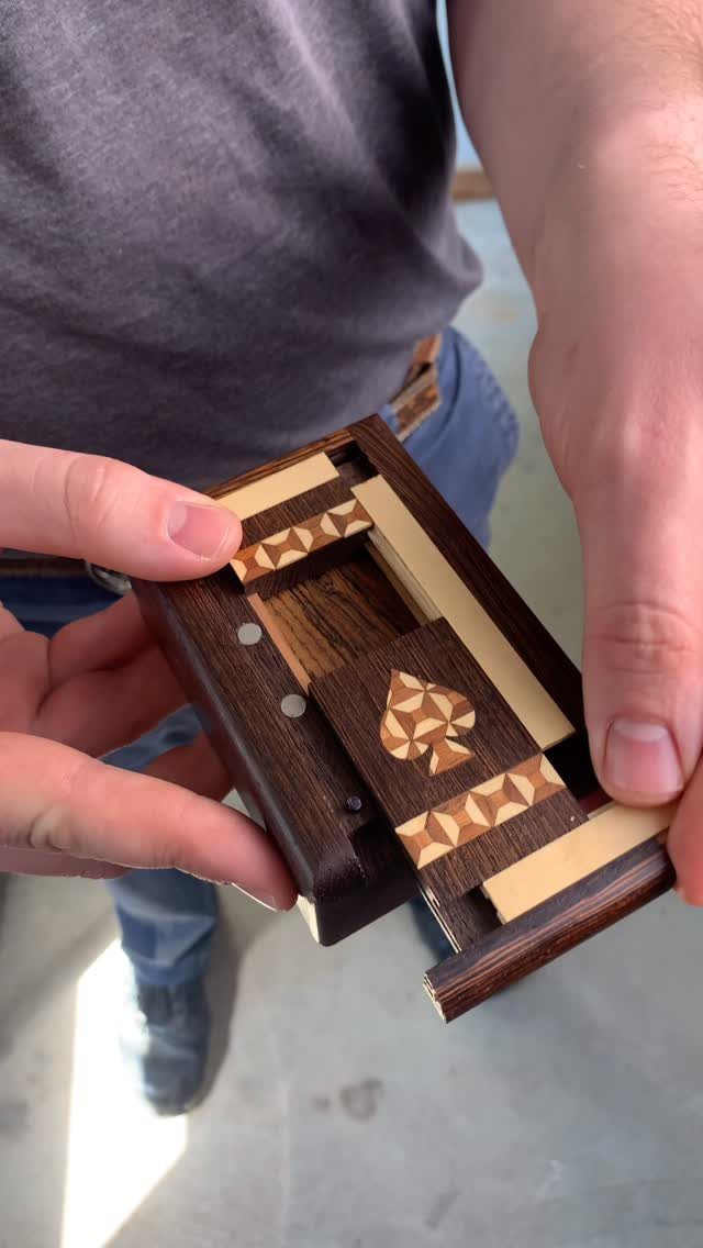Wooden box with a sliding panel revealing a small hidden storage compartment