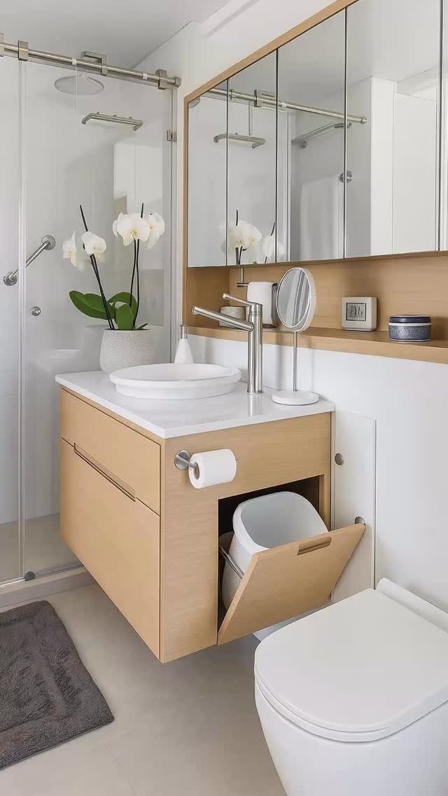 Light wood bathroom vanity with a built-in hidden trash bin compartment.