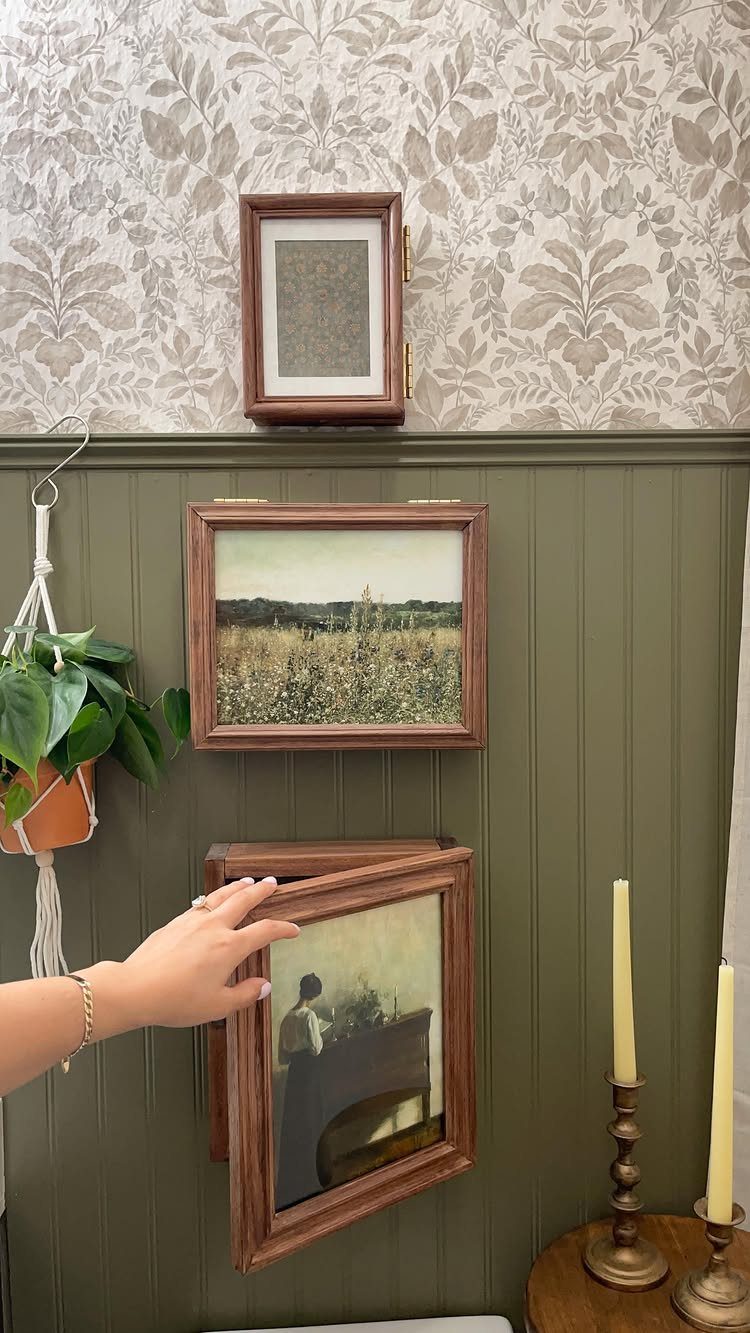 Hinged wooden picture frame being opened to reveal a hidden wall storage compartment.