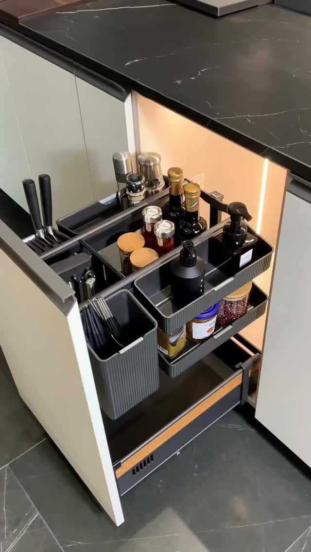 Pull-out sliding storage rack in a kitchen cabinet holding bottles and utensils.