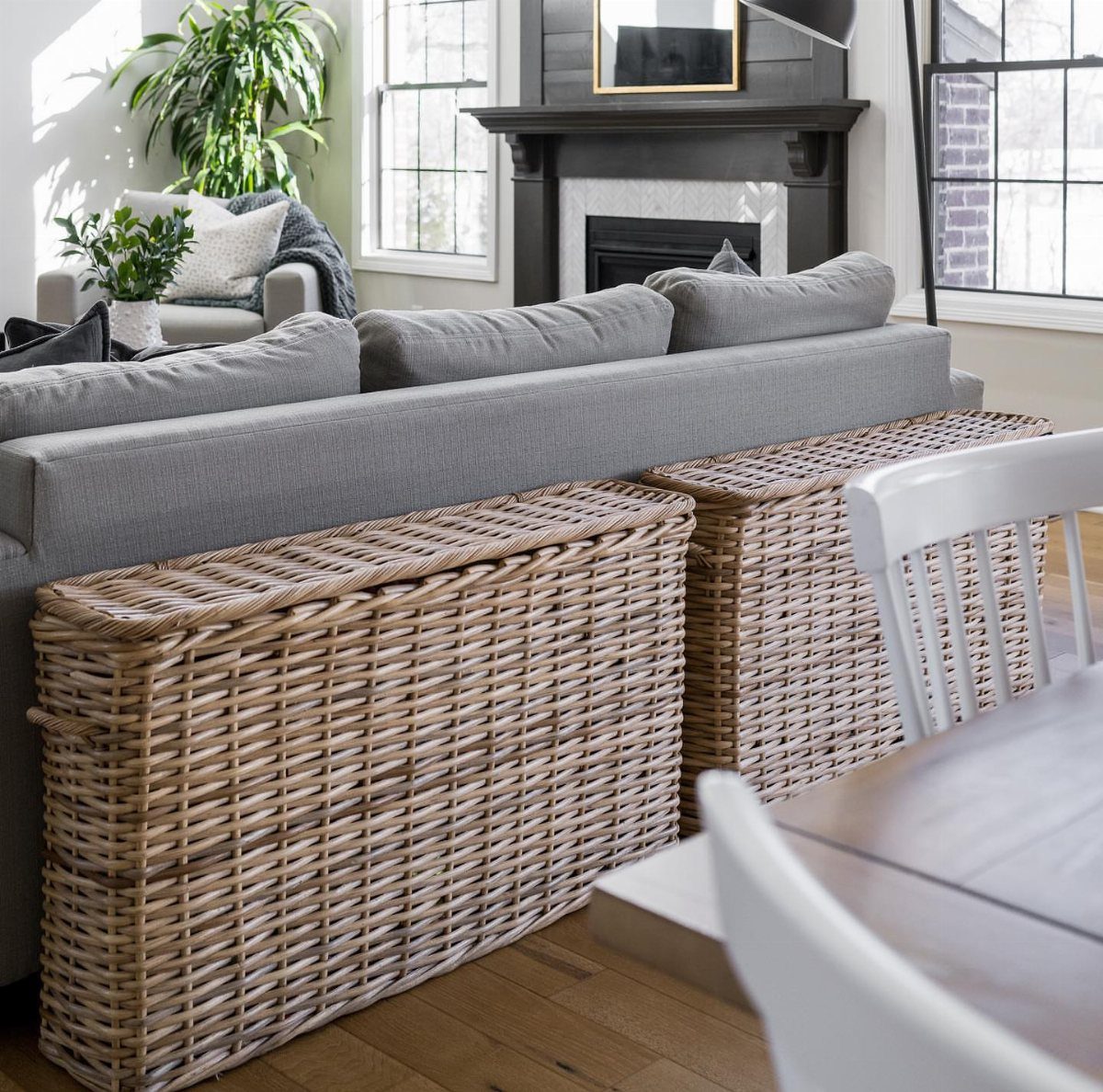 Two large woven wicker storage baskets placed behind a grey fabric sofa.