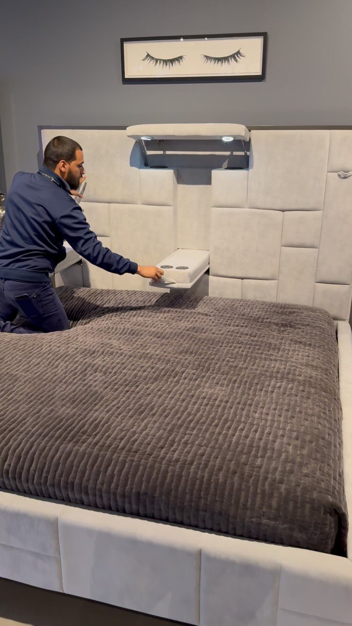 Man accessing a small hidden storage drawer built into a grey upholstered headboard
