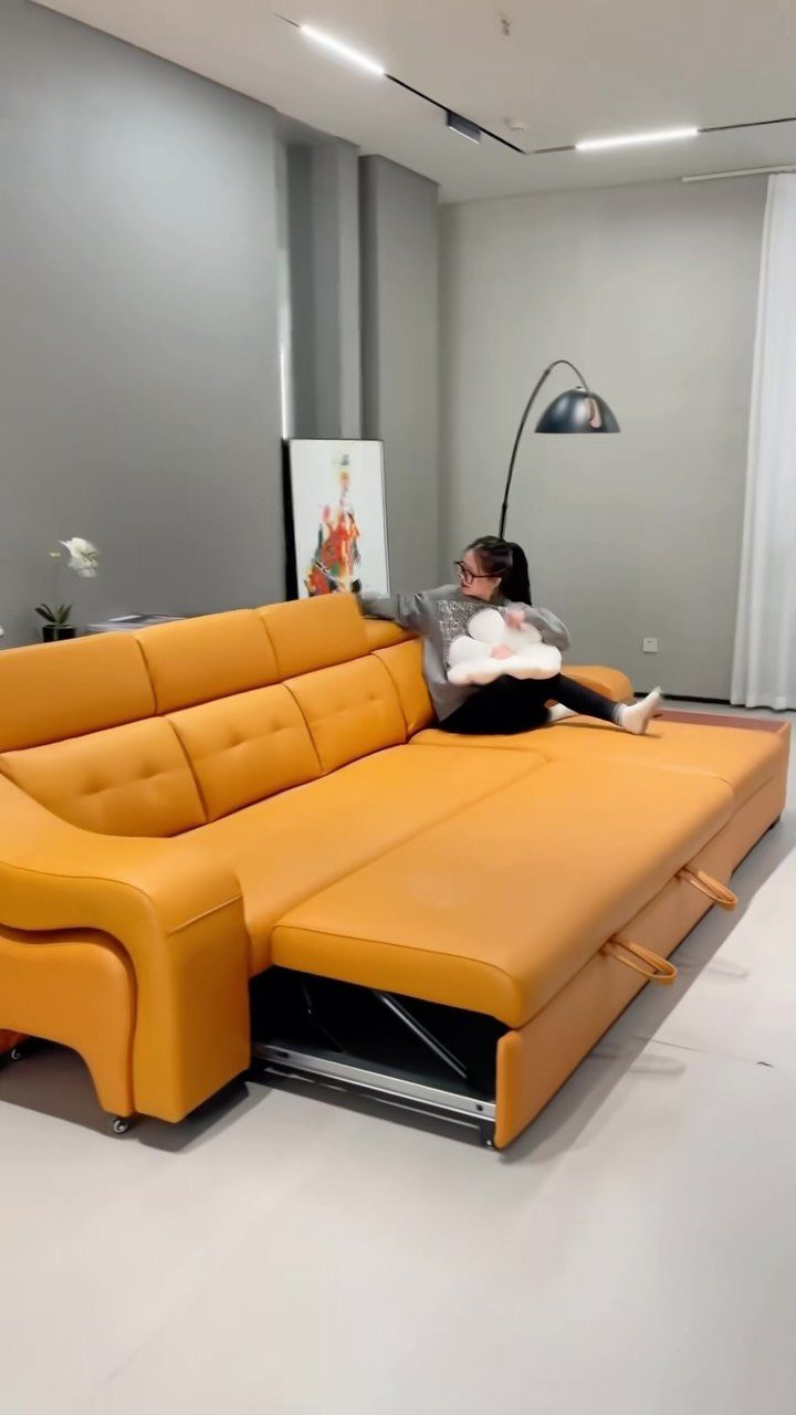 Orange leather sectional sofa with a lifted chaise revealing hidden storage underneath.