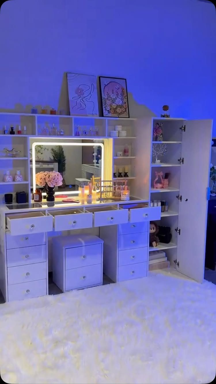 White makeup vanity with a lighted mirror, open drawers, and integrated shelving units.