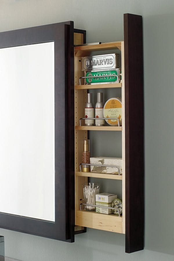 Dark wood framed mirror with an open side shelving unit containing toiletries.