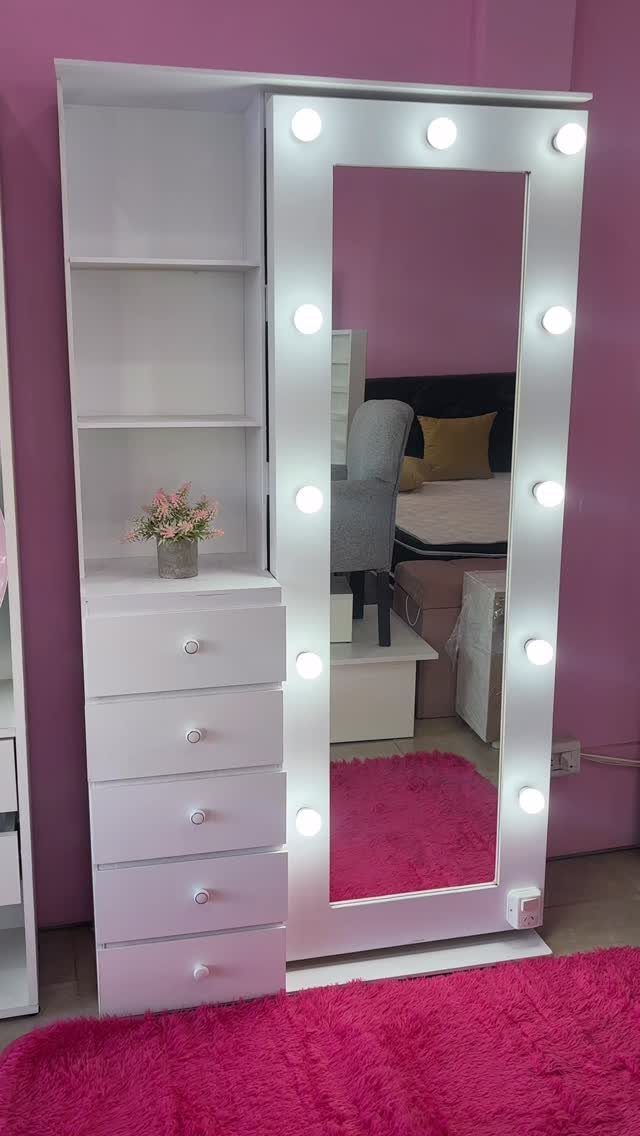White vanity unit with LED mirror, open shelves, and drawers on pink rug.