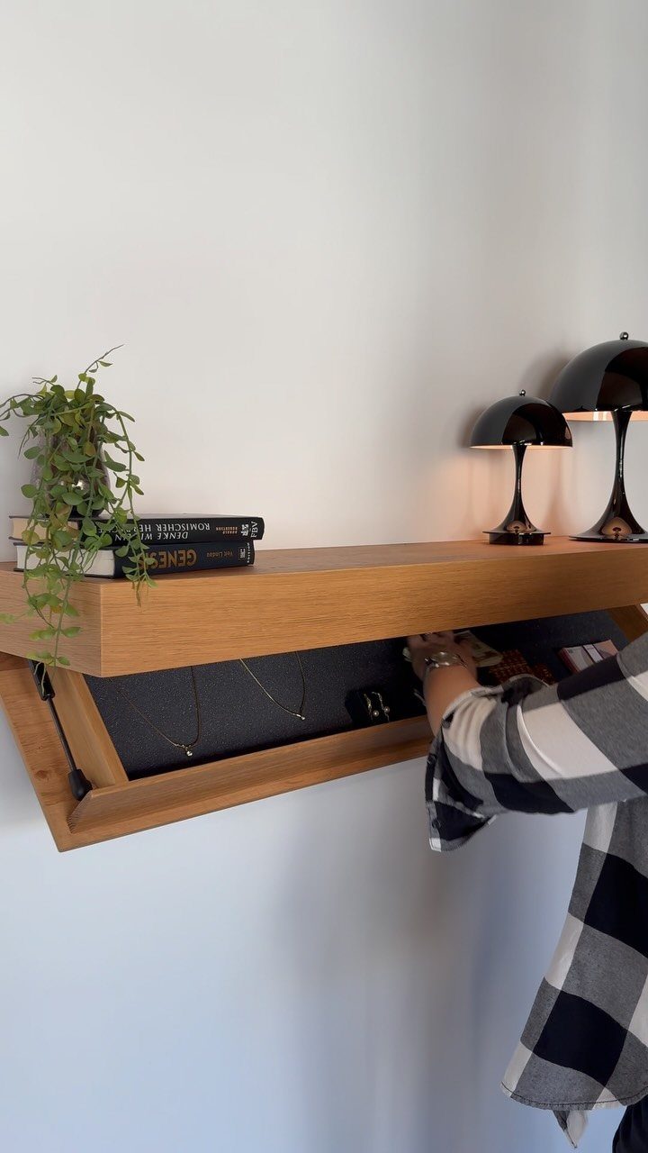 Wooden floating wall shelf opening to reveal hidden jewelry storage with necklaces inside.