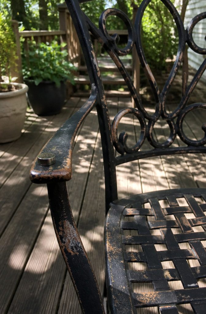 Close-up of a wrought iron chair with rust and paint chipping.