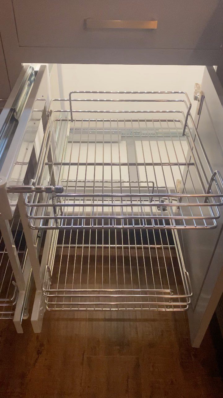 Two-tier chrome wire pull-out organizer inside a white kitchen corner cabinet.