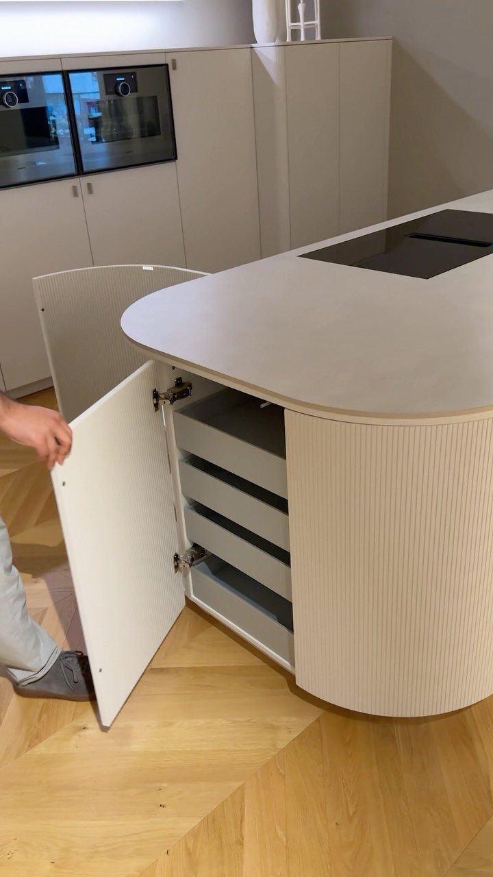 Rounded white kitchen island cabinet with fluted detailing and internal pull-out storage drawers.