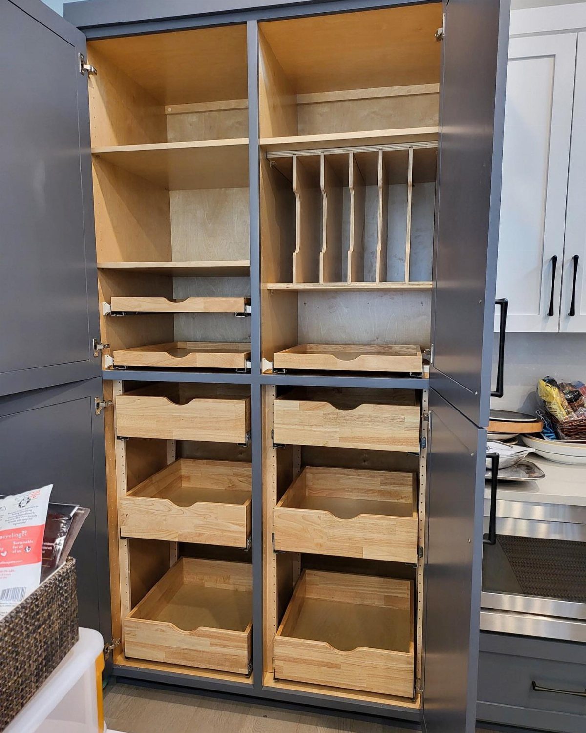 Grey built-in pantry cabinet with light wood interior shelves and pull-out drawers.