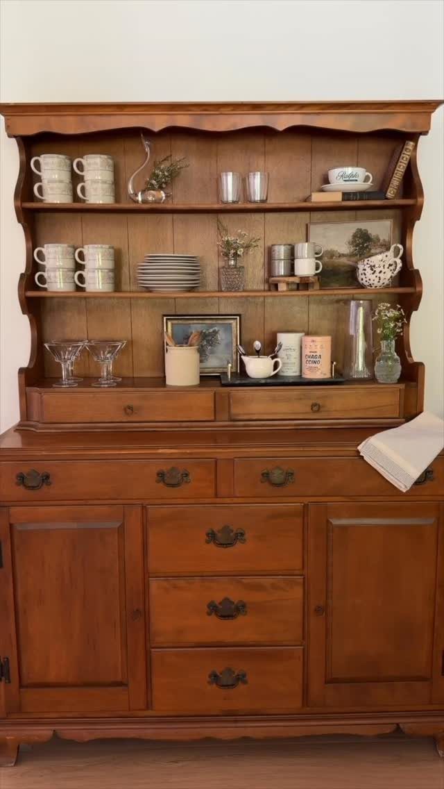 Wooden freestanding kitchen hutch with open shelves and closed lower storage cabinets.