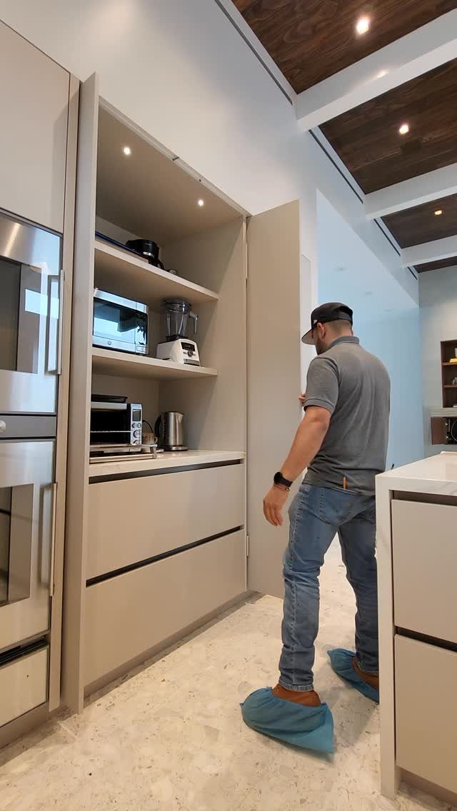 Pocket-door kitchen cabinets slid open to reveal a built-in appliance storage area.