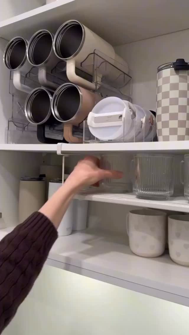 Hand pulling out a white sliding storage tray from a white kitchen cabinet.