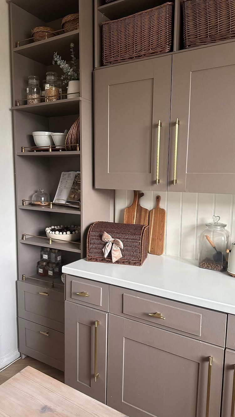 Taupe kitchen cabinets with brown wicker baskets stored on the top open shelves.