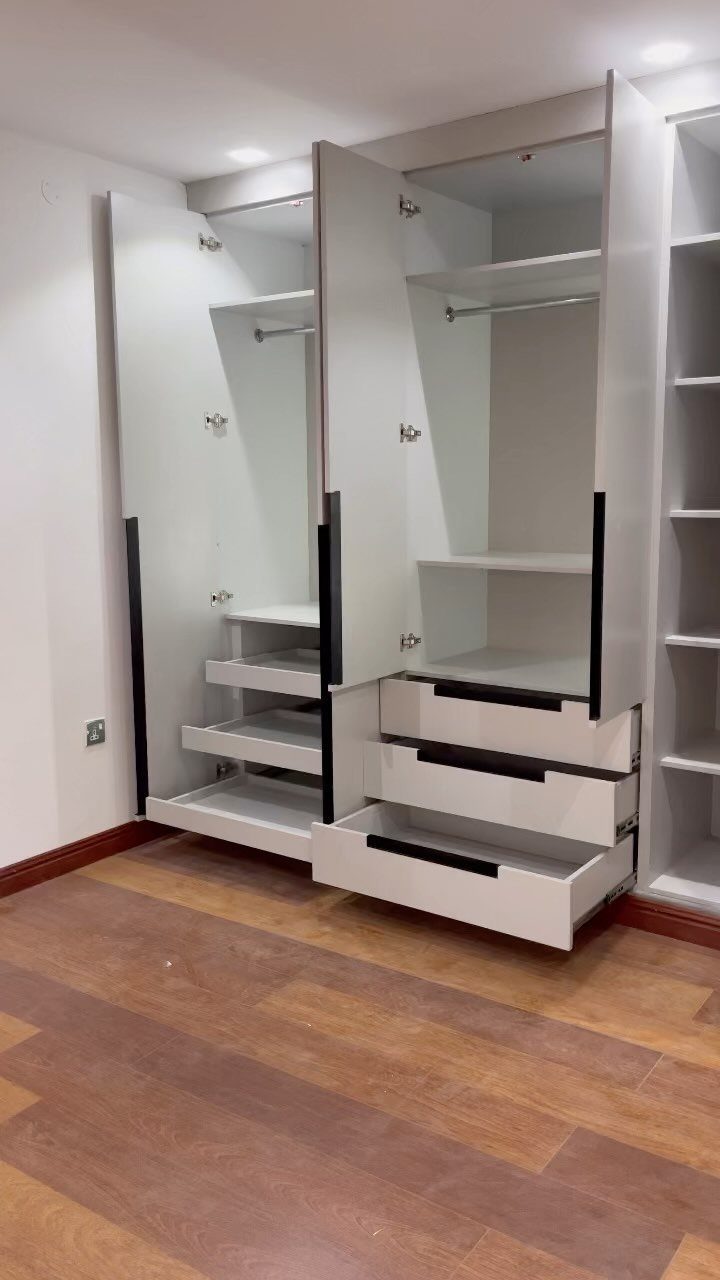 White built-in wardrobe with hanging rods and drawers at the base.