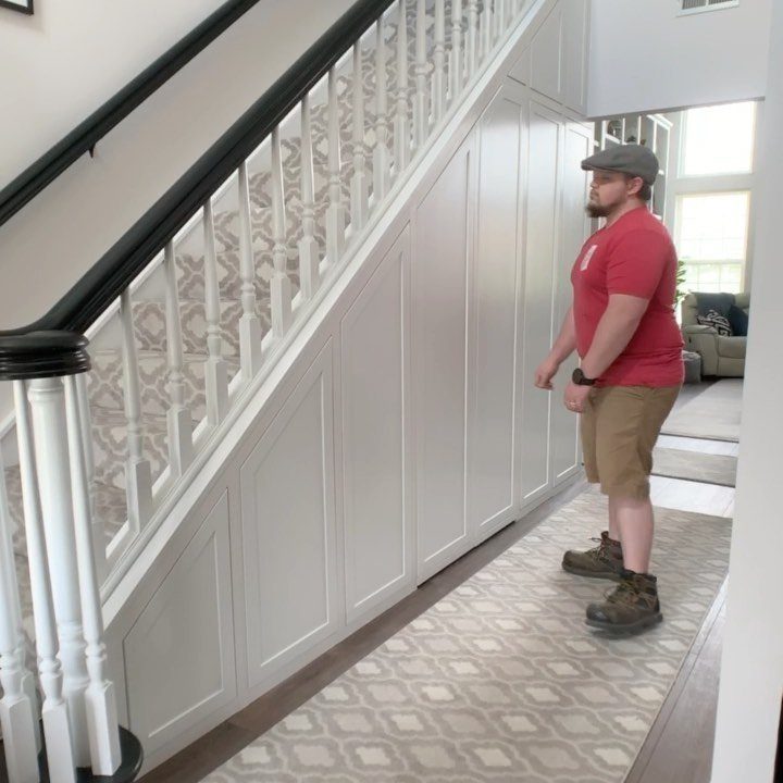 White built-in cabinets installed under a staircase with a man standing beside them.