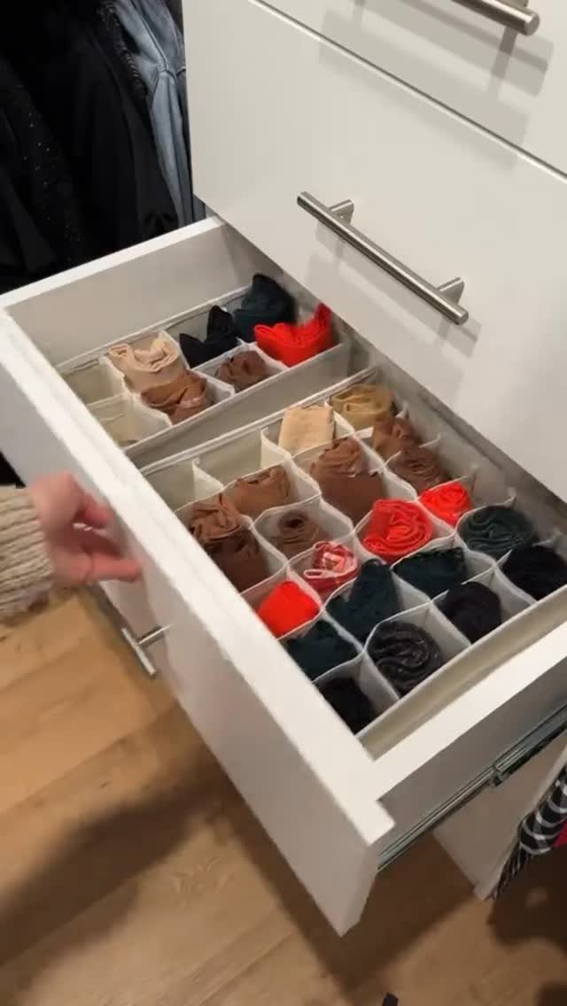 White dresser drawer with clear compartment organizers holding neatly rolled colorful socks.
