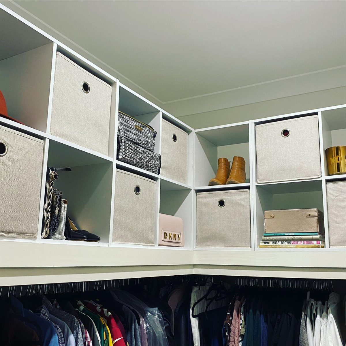 White modular cube shelving with beige fabric bins and shoes in a closet.