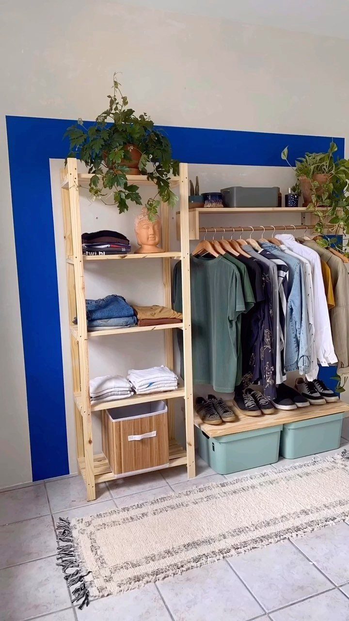 Wooden open closet system with shelving and hanging rail against a blue wall.