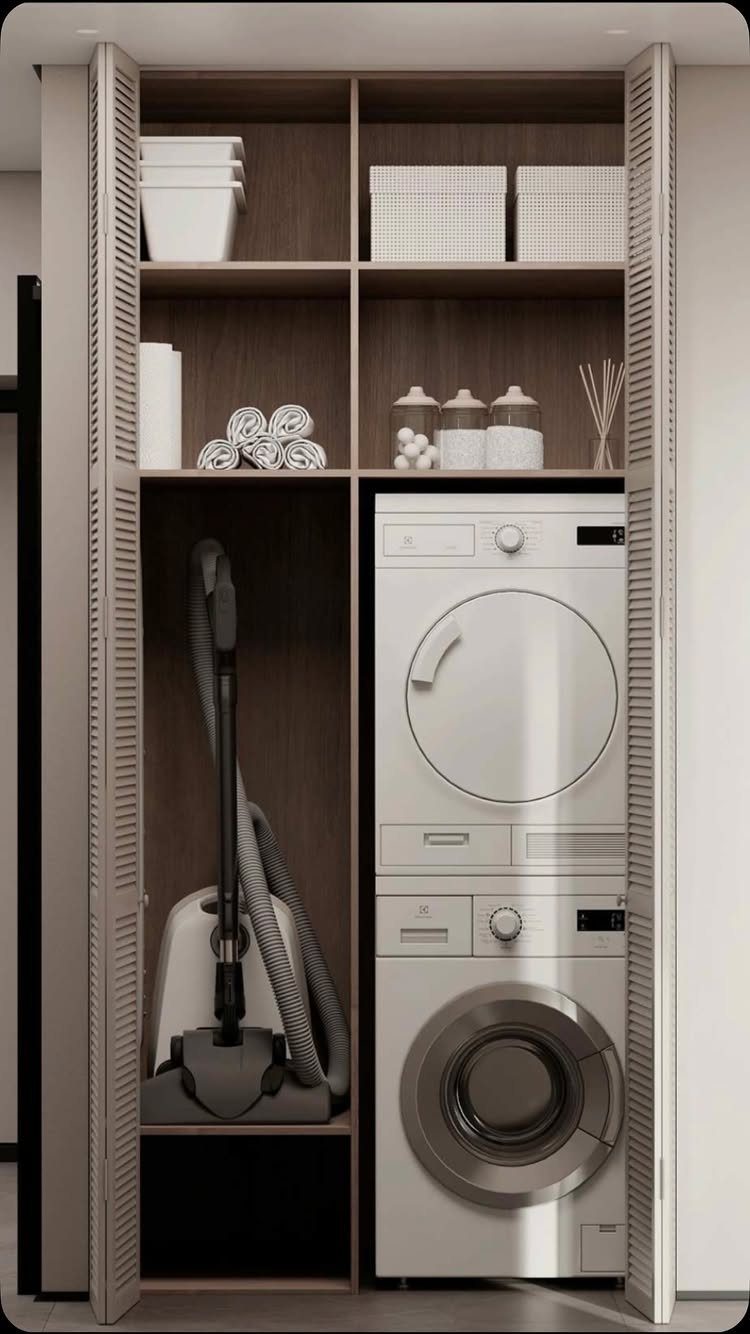 Utility closet with tall shelves containing a stacked washer dryer and vacuum cleaner.