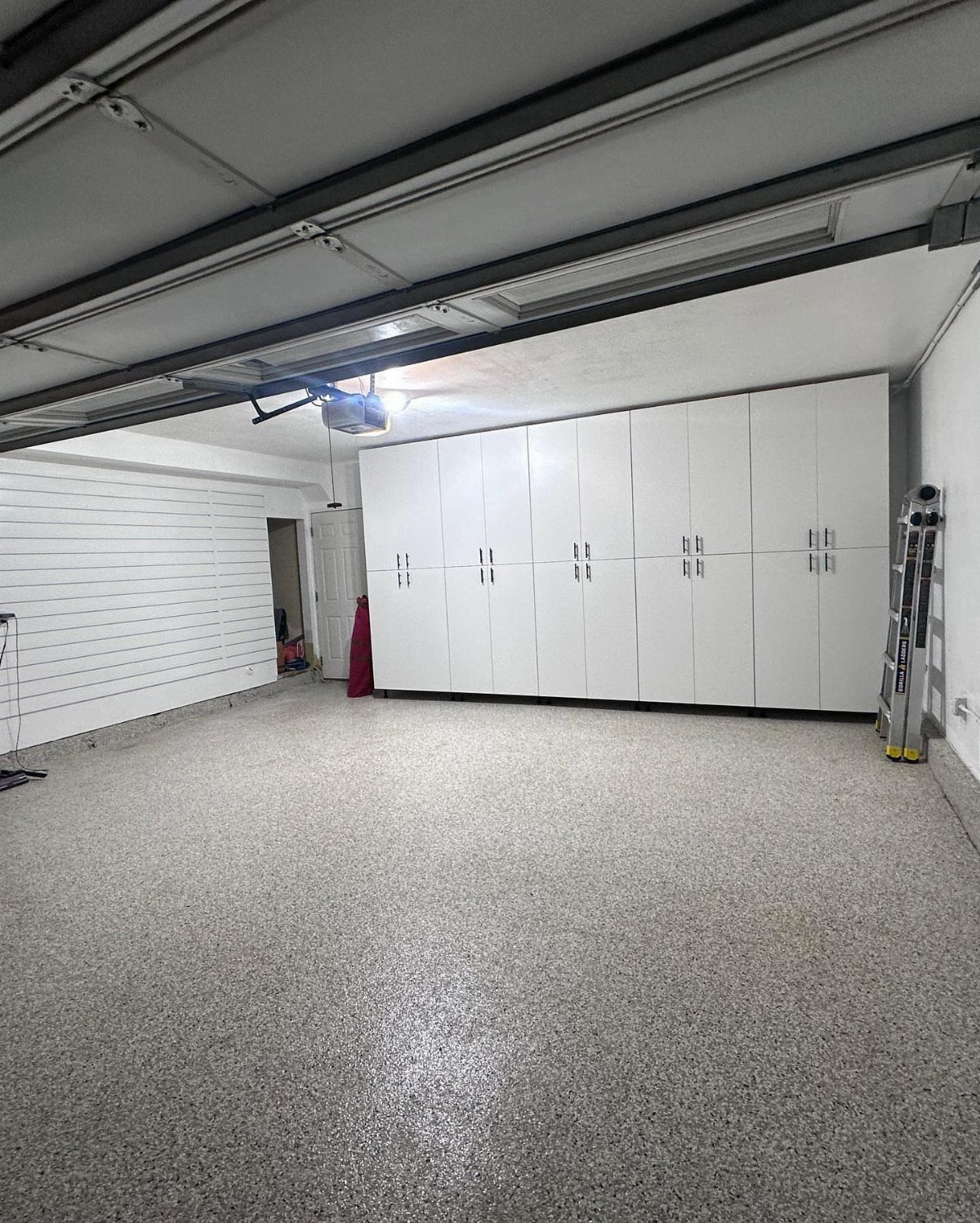 White floor-to-ceiling storage cabinets lining the wall of a clean, modern garage.