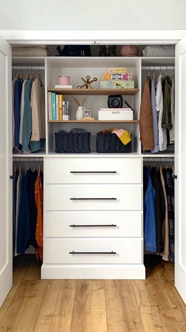 Small reach-in closet with central white drawers and shelving between hanging clothes sections.