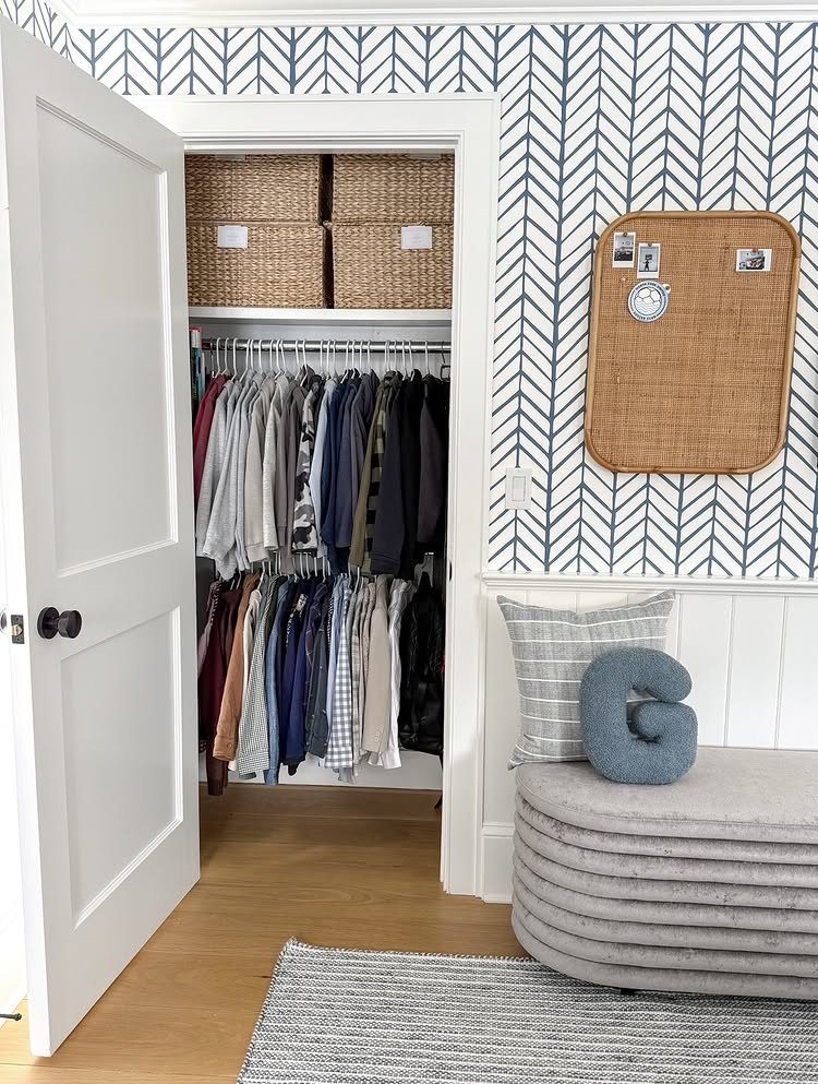Small reach-in closet with double hanging rods and wicker storage baskets on top shelf.