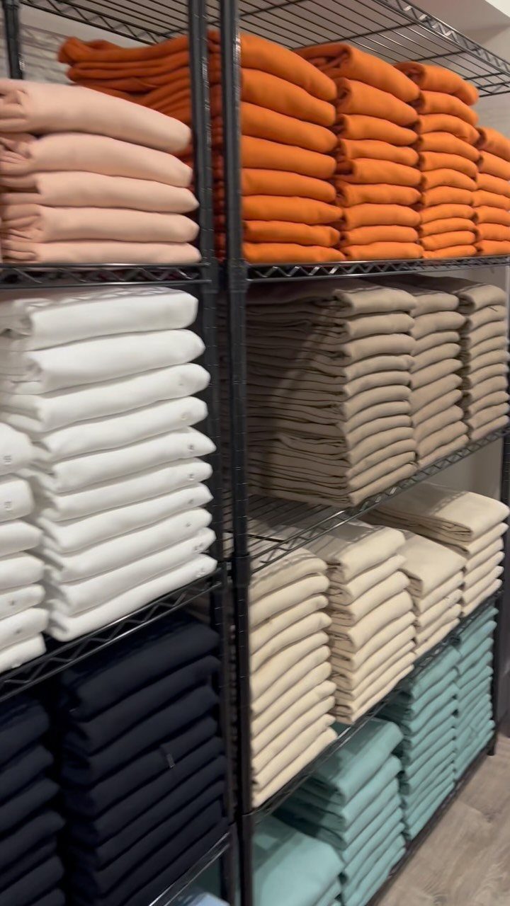 Folded clothing in colorful stacks organized on black wire closet shelving units.