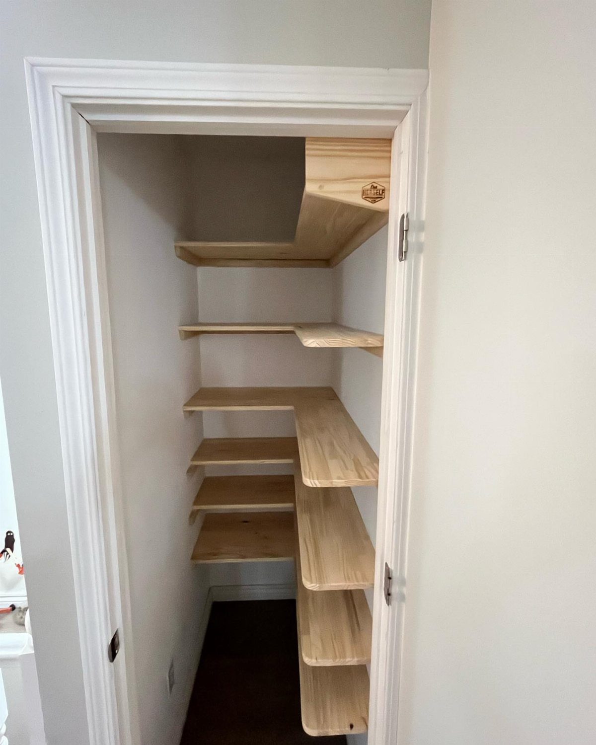 Natural wood solid shelving installed inside a small white reach-in closet.
