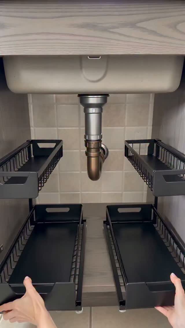 Black pull-out sliding drawers installed under a kitchen sink for organized storage.