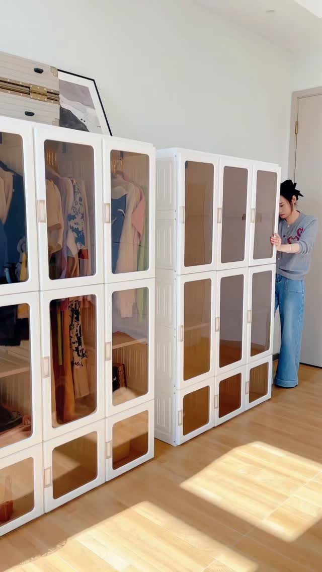 White modular plastic wardrobe units with translucent doors containing clothes in a room.