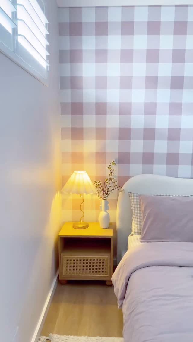 Pink and white gingham wall with a light wood nightstand and rose bedding.