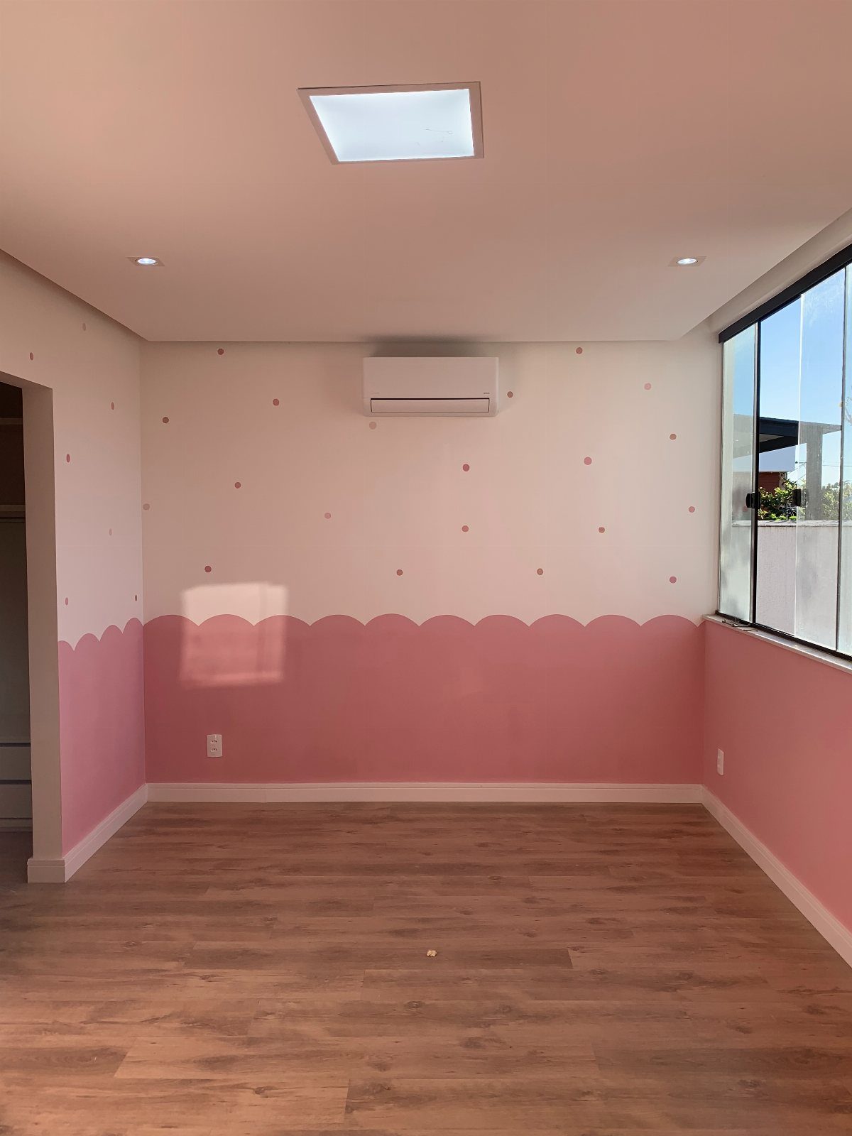 Pink scalloped paint on the lower half of white walls in a room.