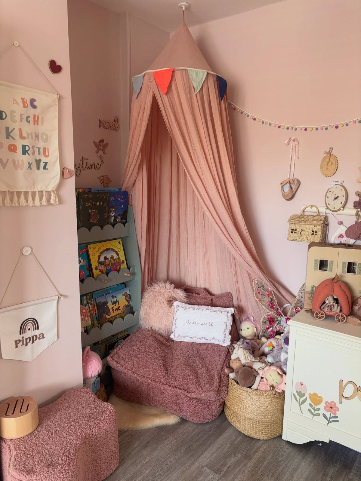 Pink toddler bedroom with a canopy tent, beanbag chair, and pink painted walls.