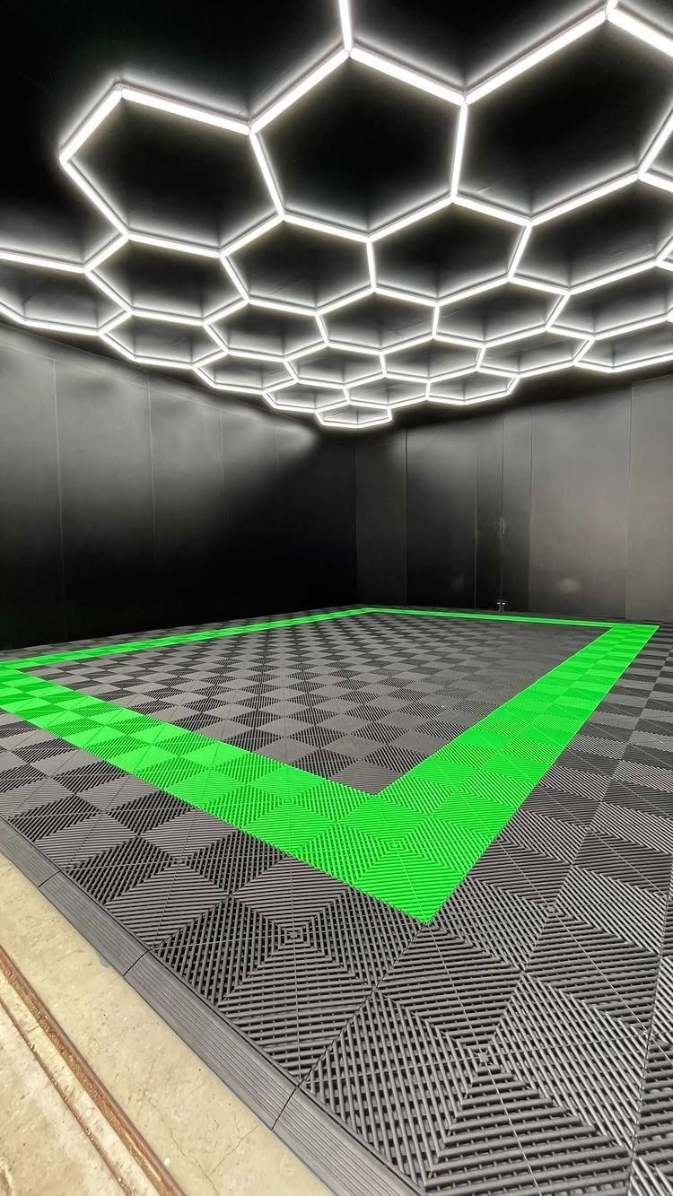 Modern garage interior with hexagonal ceiling lights and grey and green tiled flooring.