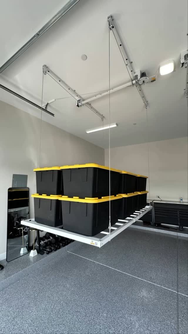 Ceiling-mounted storage rack holding black and yellow bins in a clean grey garage.