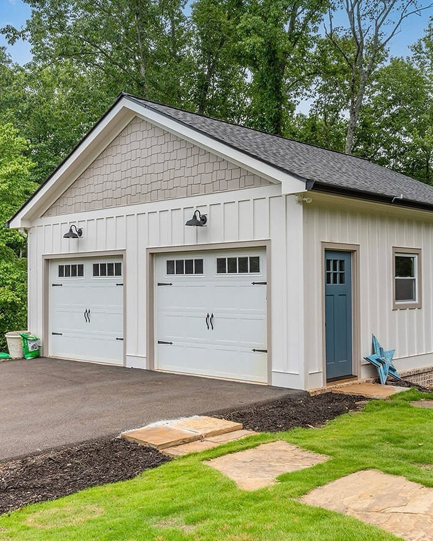 White two-car detached garage with carriage doors and a blue side entrance door.