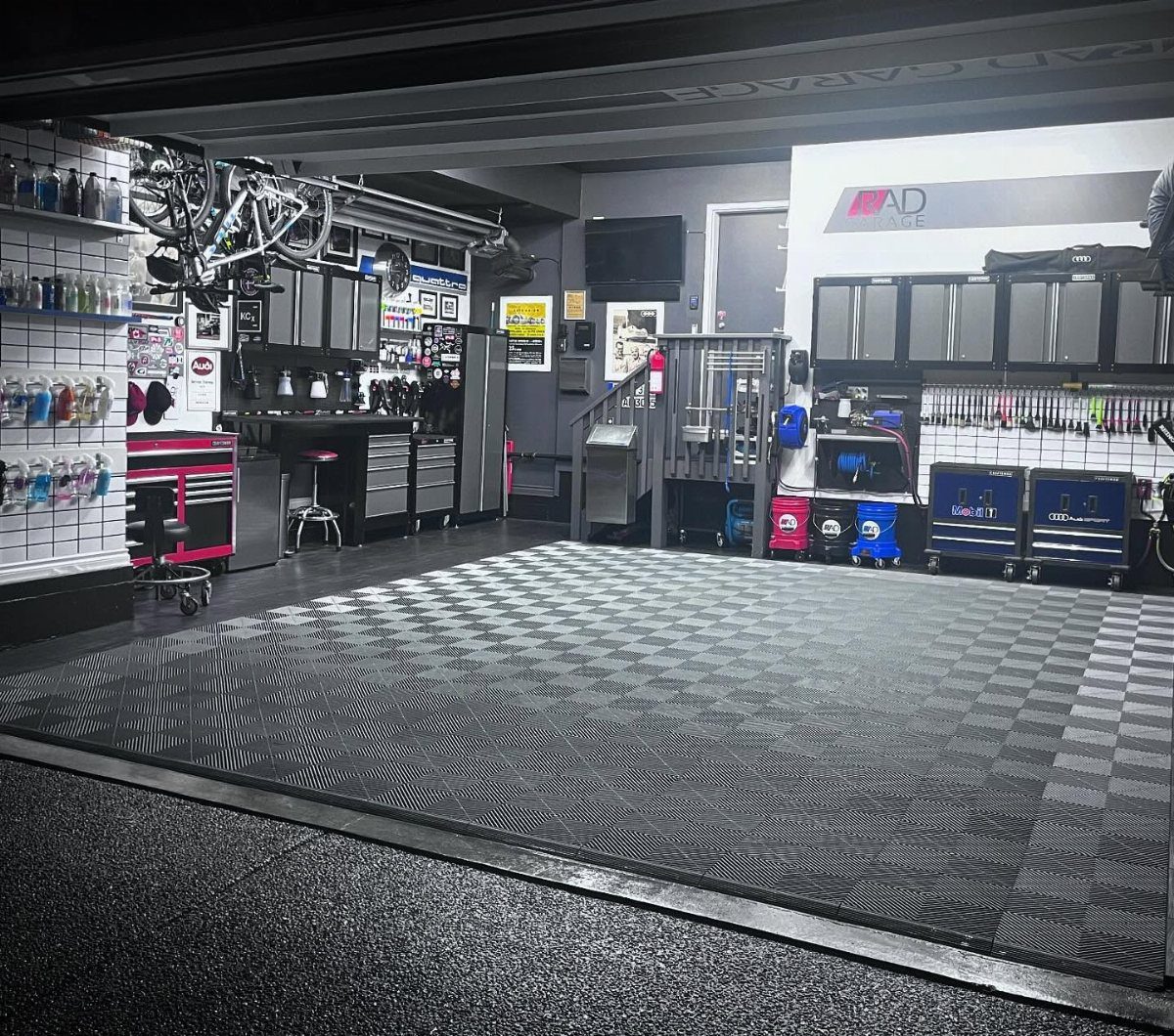 Organized garage workshop with grey tiled floors, metal cabinets, and hanging bicycles.